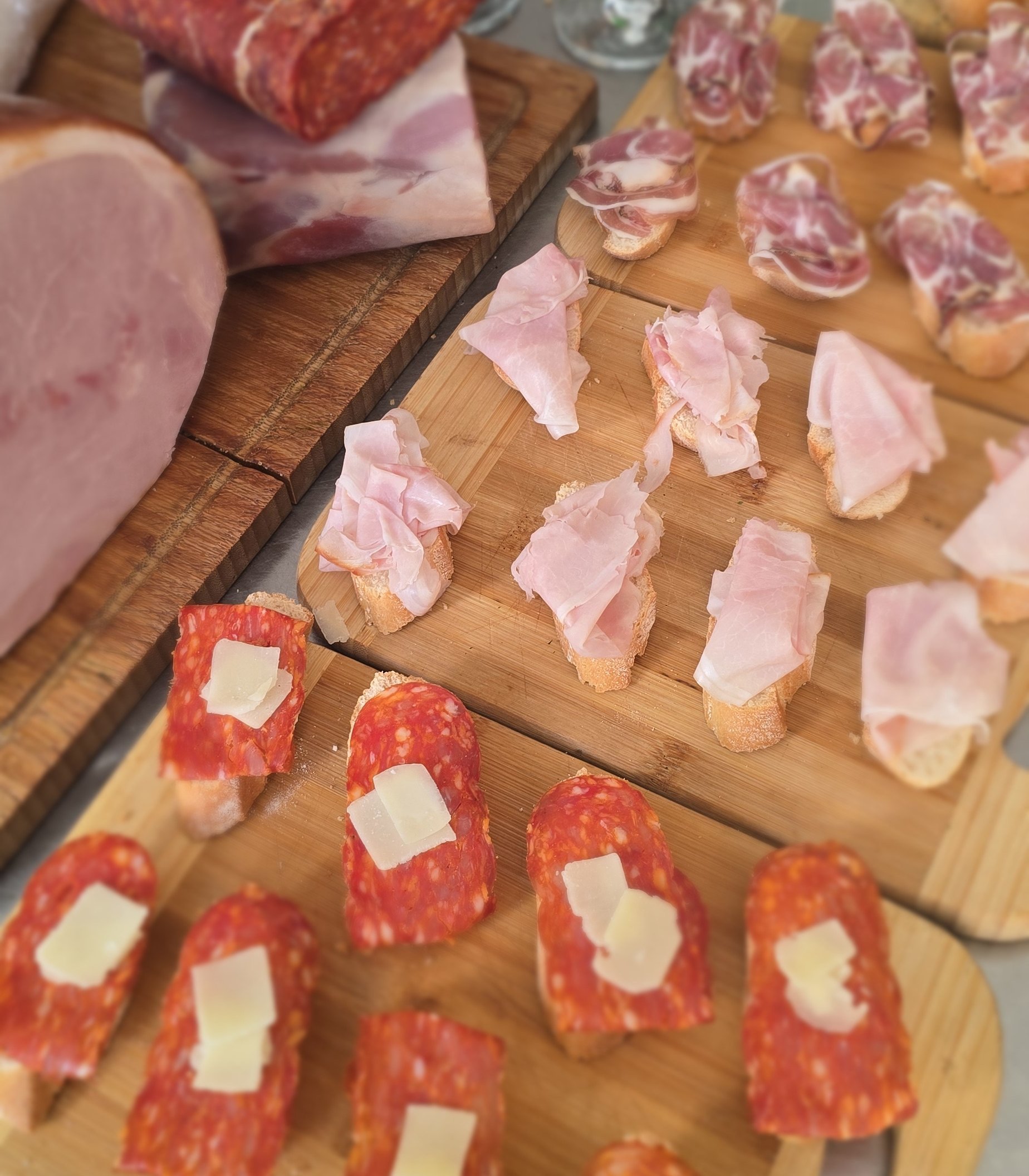 Tagliere di salumi dell'Osteria Bea Vita: coppa, prosciutto e salame su crostini di pane caldo, su tavola di legno.